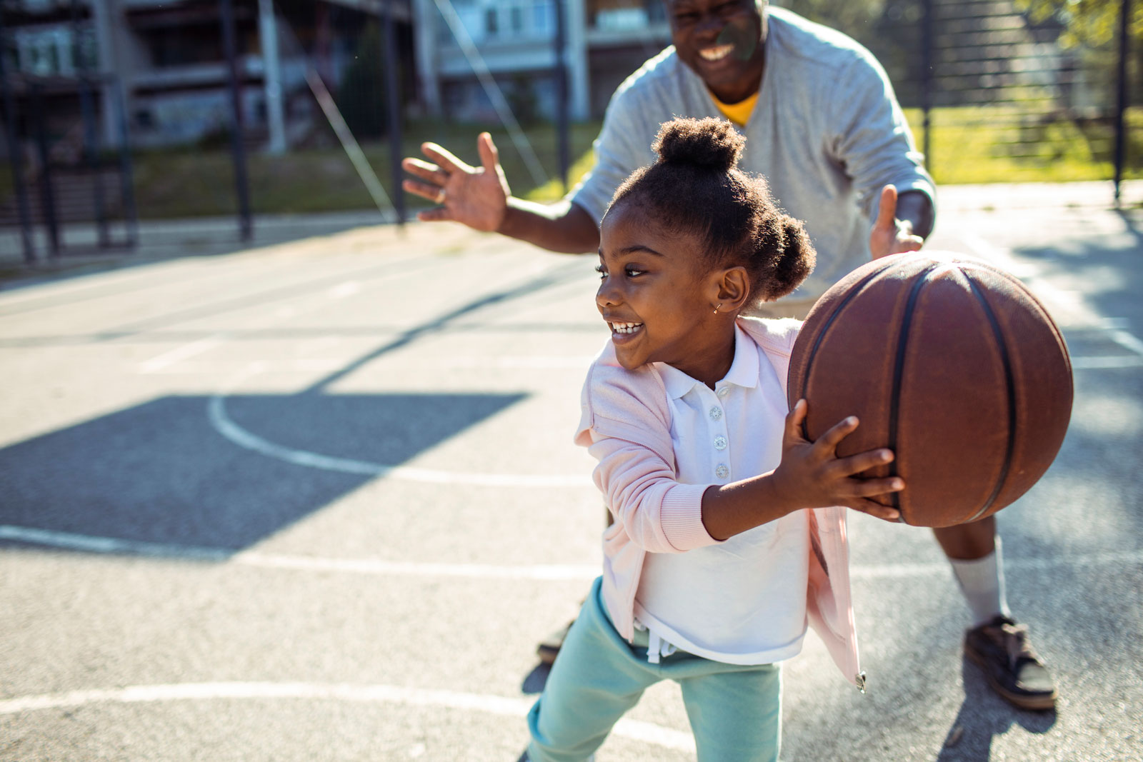 Girl playing basketball with her grandpa.