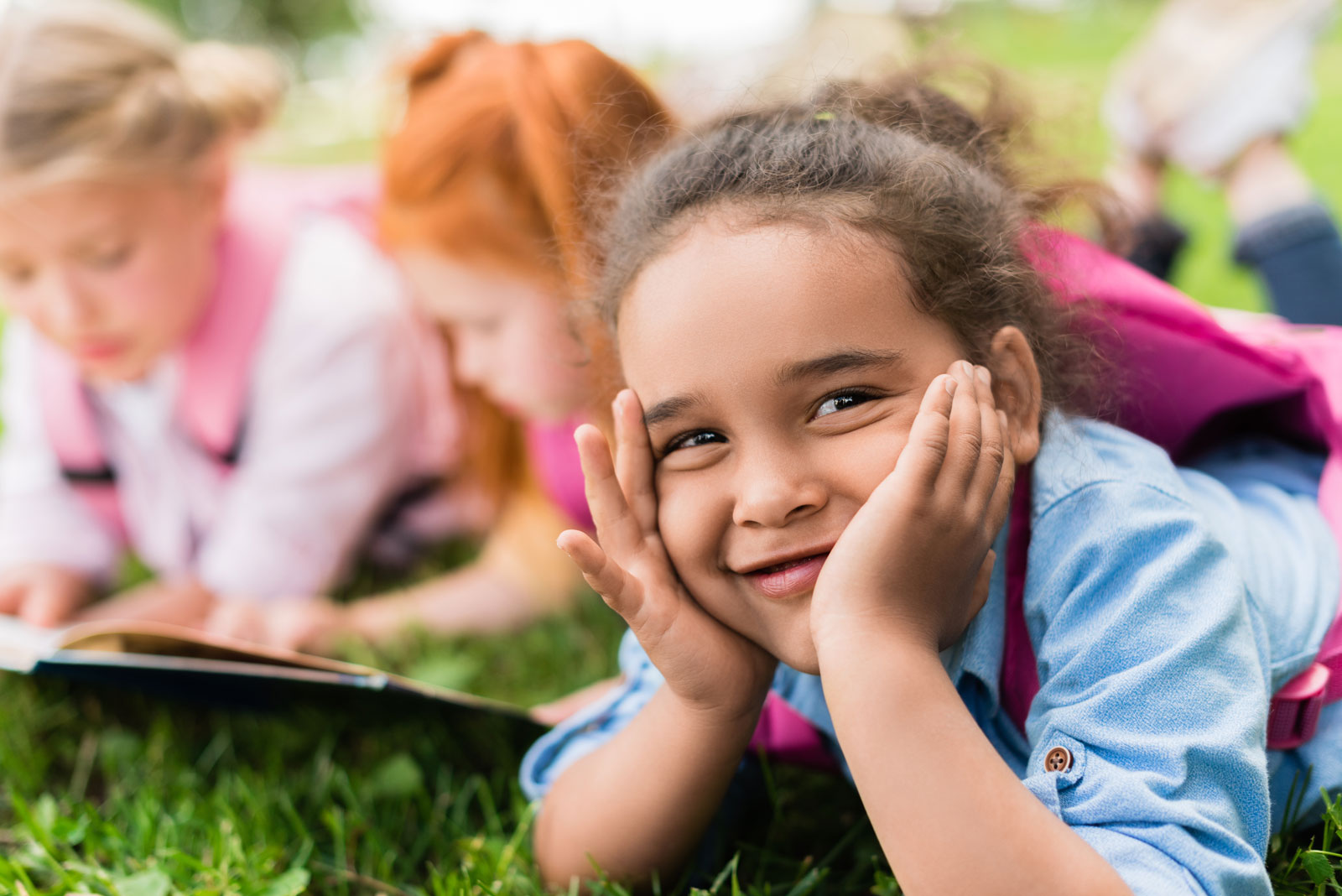 Children reading books in the grass.