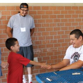 Two Native American men talking with a Native American little boy along with a women