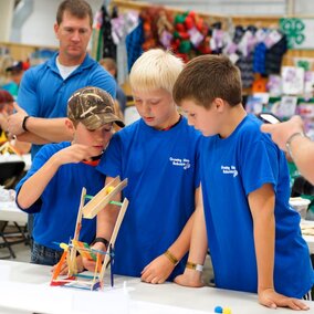 three boys in blue shirts with a catapolt