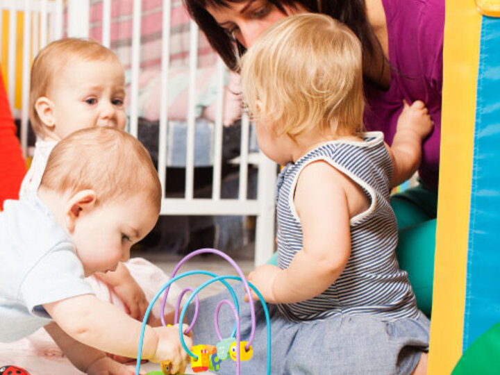 Woman playing with babies on the floor.